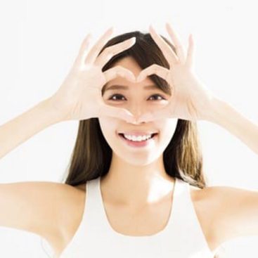 woman holding up hands in a heart shape